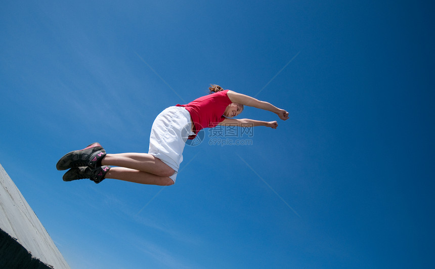 美丽的女人跳上天空蓝色成人活力快乐运动空气叶子女士运动员闲暇图片