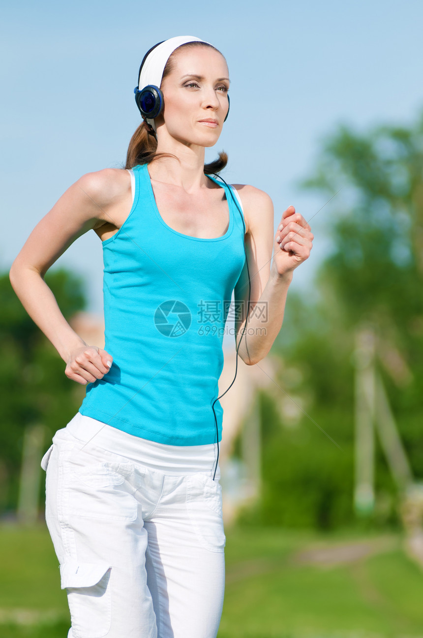 美丽的女子在绿色公园中奔跑跑步森林快乐运动饮食精力女性女士音乐女孩图片