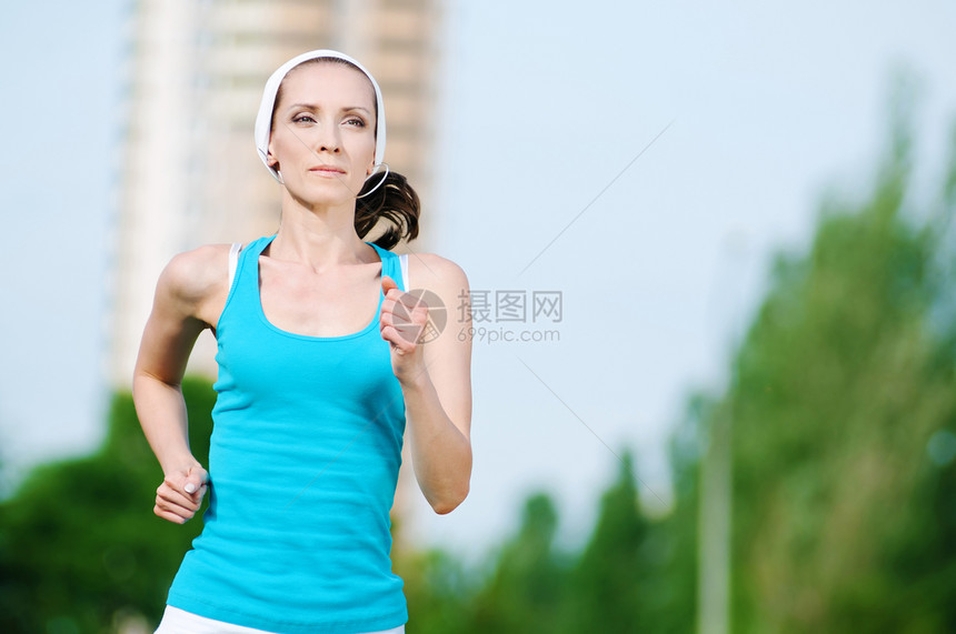 美丽的女子在绿色公园中奔跑肌肉精力街道女性森林跑步季节身体闲暇运动图片