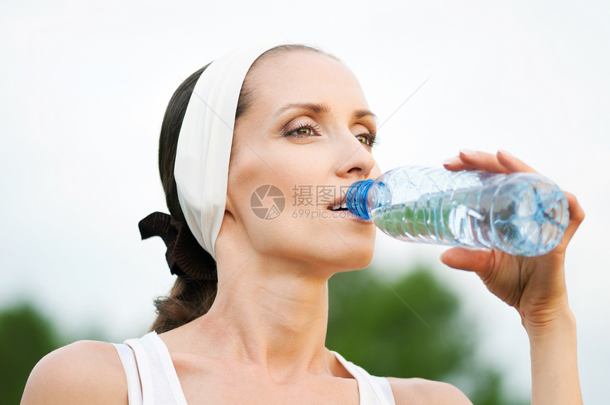 户外运动中的妇女饮用水流动保健成人行动运动员天空运动蓝色慢跑女士图片