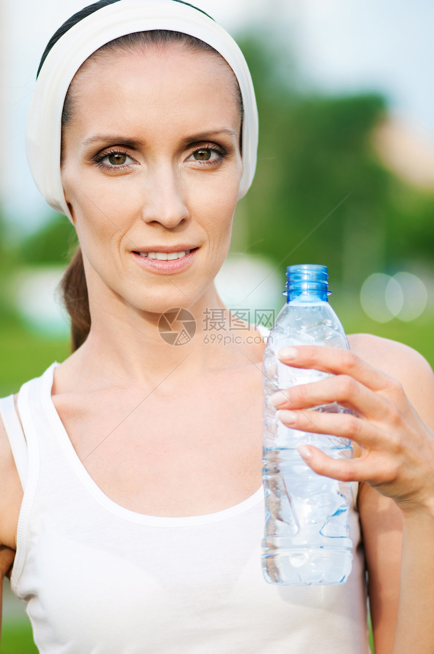 户外运动中的妇女饮用水矿物保健蓝色女孩运动有氧运动公园运动装训练瓶子图片