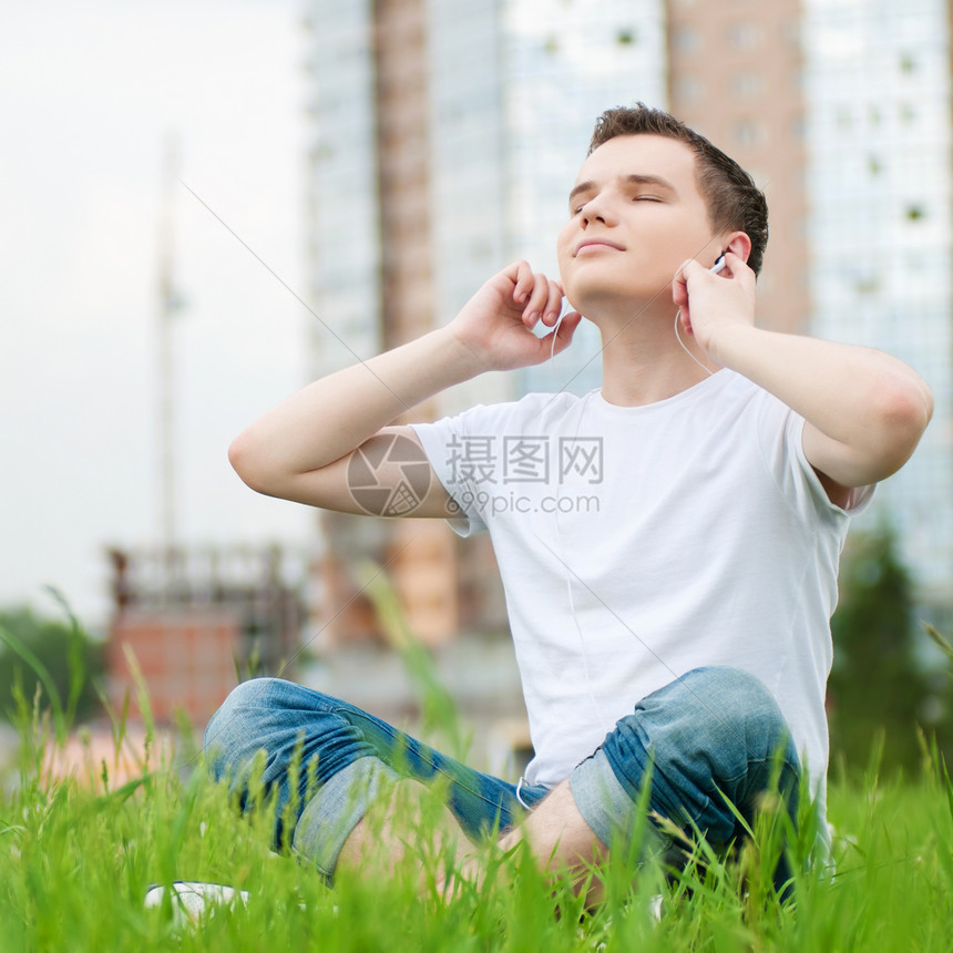 有耳机的有吸引力的年轻人音乐青少年闲暇男生自由街道男人天空美丽日光浴图片