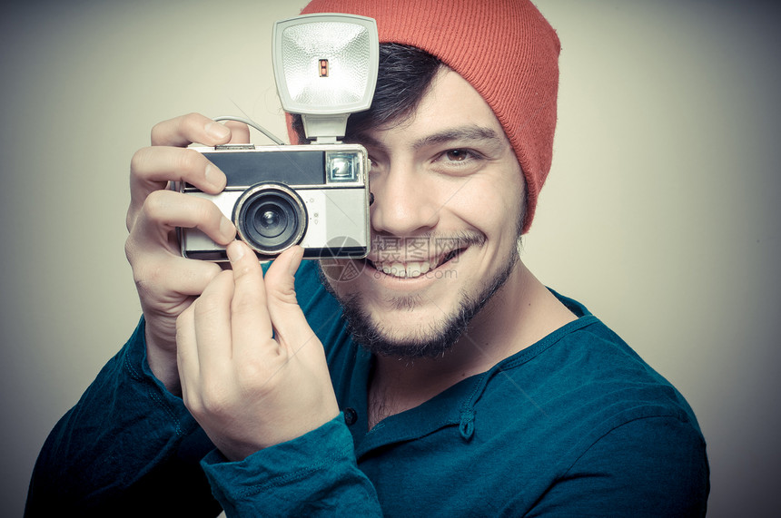 年轻时尚男子拿着旧相机帽子成人照片工作室老相机发型橙色男性拍照衬衫图片