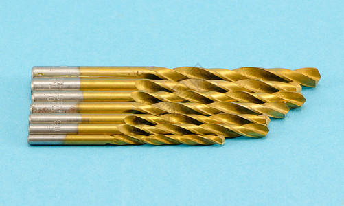蓝色上不同大小的金色钻探比特金子工具木制品尺寸硬件车削工作技术机器乐器背景图片
