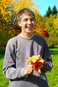 有叶子的少年微笑衣服公园快乐男性青少年黑发花束阳光小伙子背景图片