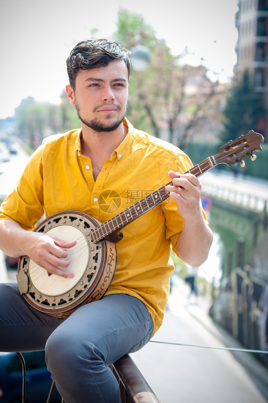 玩班卓琴的年轻嬉皮士音乐家年轻人衬衫城市音乐乐器黄色图片