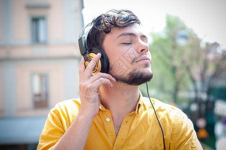 听音乐的青春青年乐趣年轻人黄色衬衫音乐耳机阳台城市背景图片