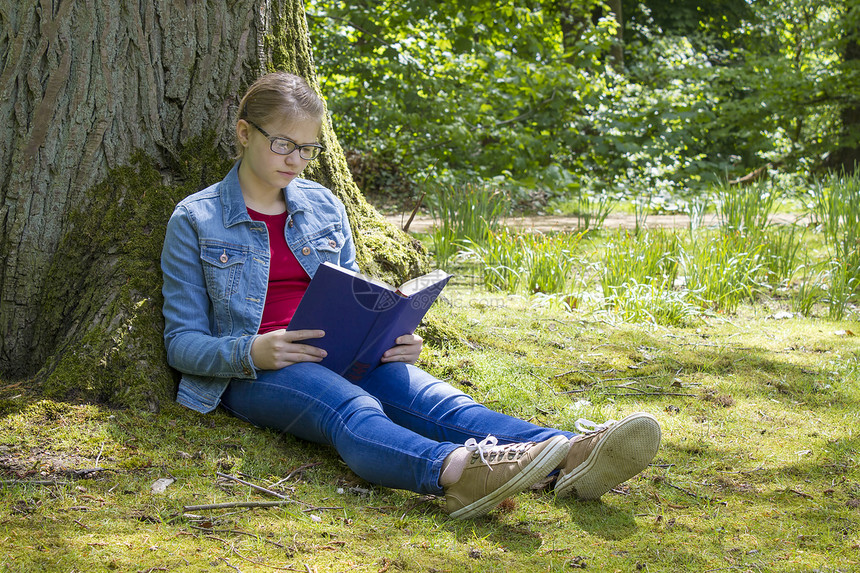 春日在公园读书的年轻女孩草地家庭作业乐趣休息金发女郎娱乐牛仔裤眼镜教育喜悦图片