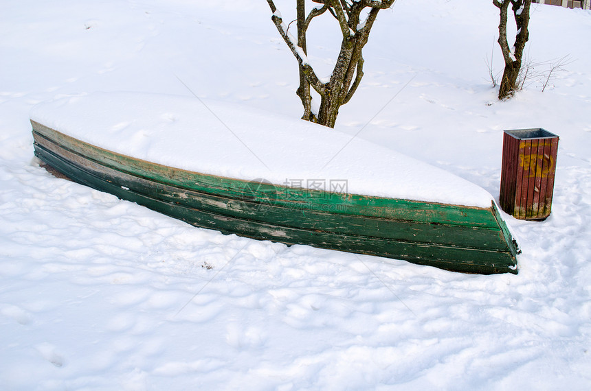 翻倒在雪底的旧木船图片