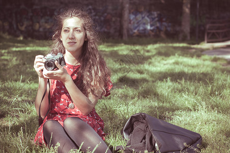 用旧相机的老古董女人公园礼服长发老相机红色背景图片