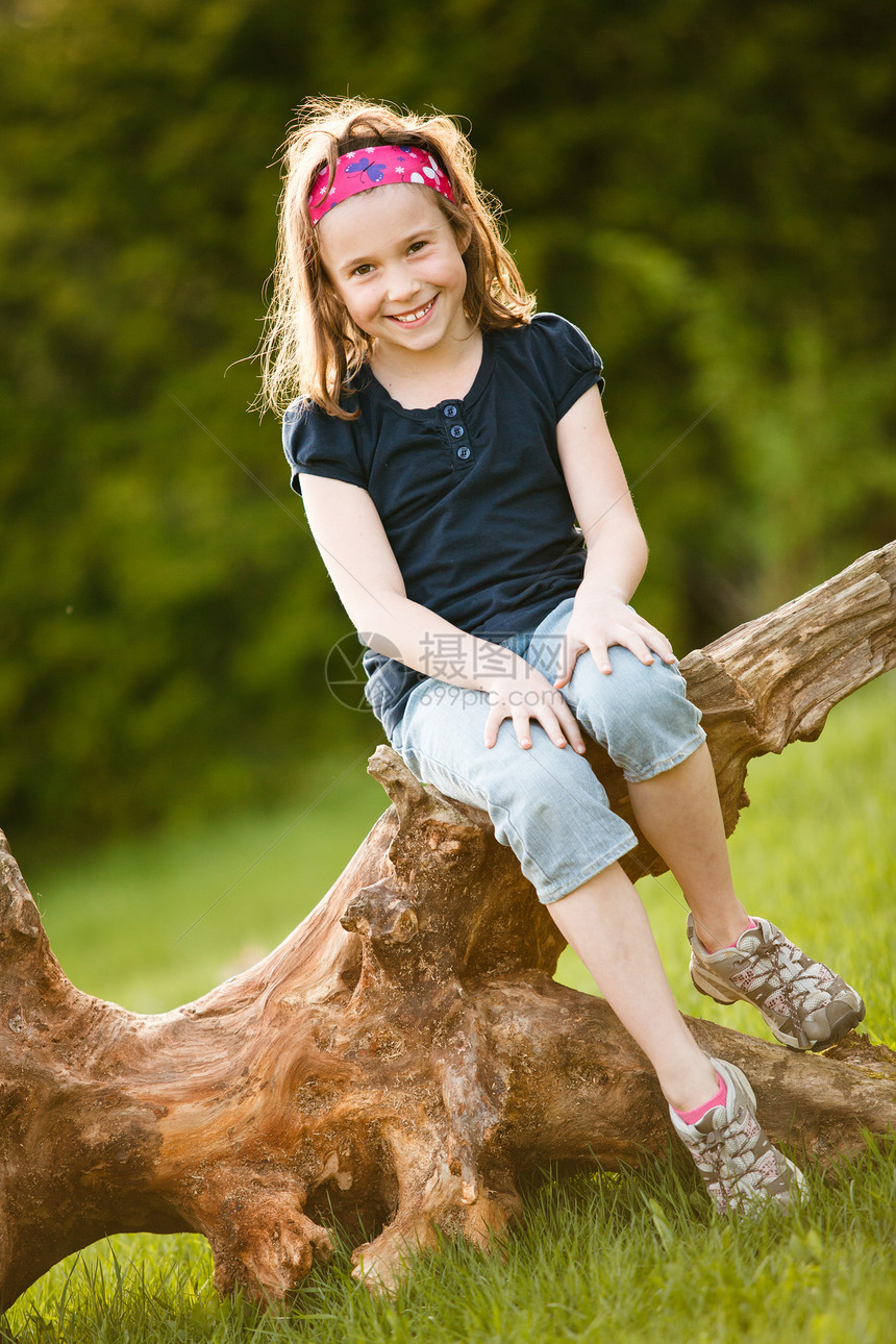 坐在树干上的女孩童年微笑孩子黄金女性时段太阳图片