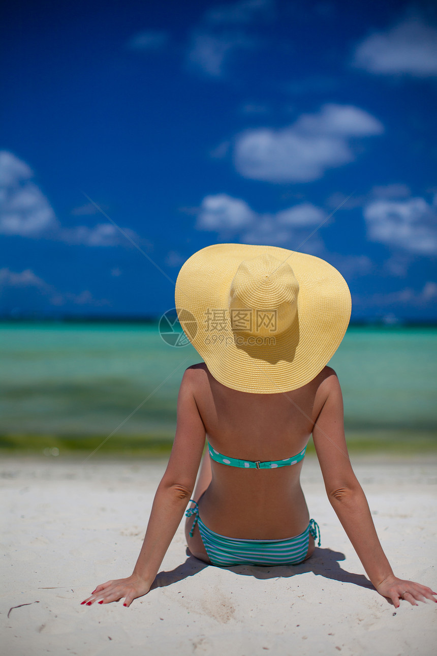 坐在沙滩上戴帽子的女人晴天成人游泳衣热带天空女性白色比基尼泳装女士图片