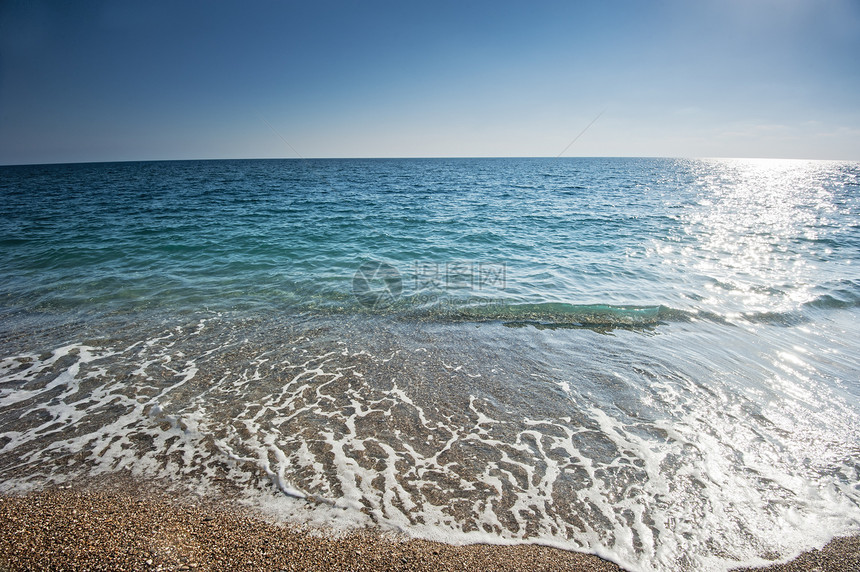 在沙沙滩上喷洒的海泡沫边缘假期太阳气候海景蓝色冲浪场景金子游客图片