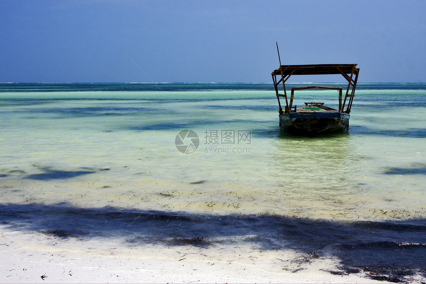 沙滩海草和坦桑河的船海洋浅蓝色海滩支撑独木舟木头天空小岛海藻石头图片