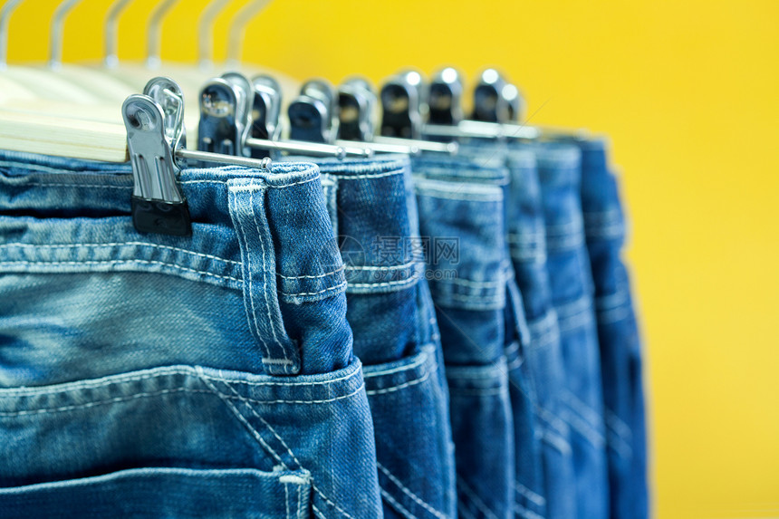 商店里挂着一排蓝色牛仔裤接缝零售男性牛仔布展示纺织品壁橱团体陈列室服装图片
