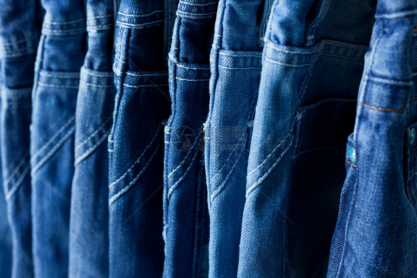 商店里挂着一排蓝色牛仔裤零售纺织品展示衣服服装裤子织物架子接缝材料图片