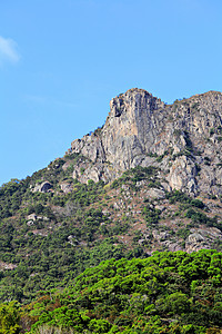 禁鸣喇叭香港的狮子岩石山绿色植物爬坡喇叭草地蓝色天空岩石背景