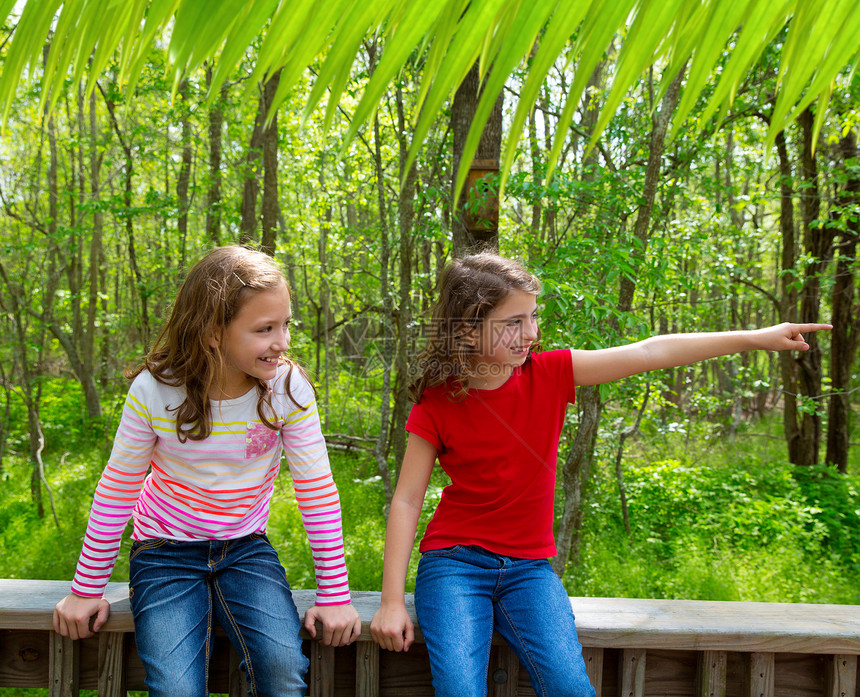 儿童朋友玩把手指指向丛林公园的游戏森林孩子们乐趣公园姐妹女孩们栅栏童年朋友们幸福图片