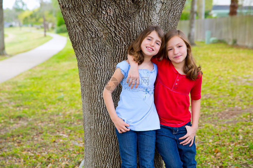 女孩们在公园树上耳边低语幸福眼睛树木拥抱朋友们花园家庭蓝色草地牛仔裤图片