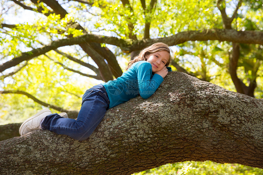 躺在树枝上躺着的女女童女性蓝色树干牛仔裤金发花园说谎童年树木孩子图片