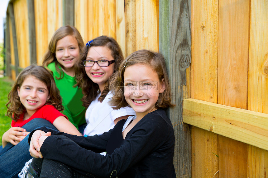 一连排的格里尔斯团体在木墙上微笑冒充幸福女性团队童年眼睛公园蓝色享受家庭图片