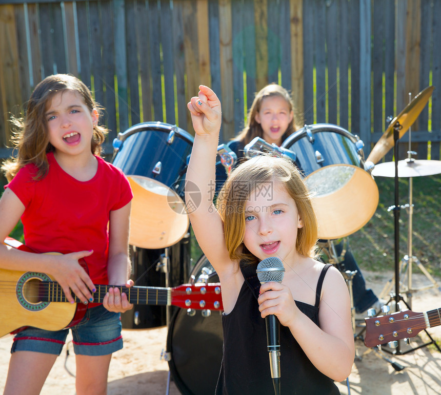 歌唱女歌手在后院现场演奏乐团闲暇鼓手岩石女孩们流行音乐孩子们栅栏眼睛童年仪器图片