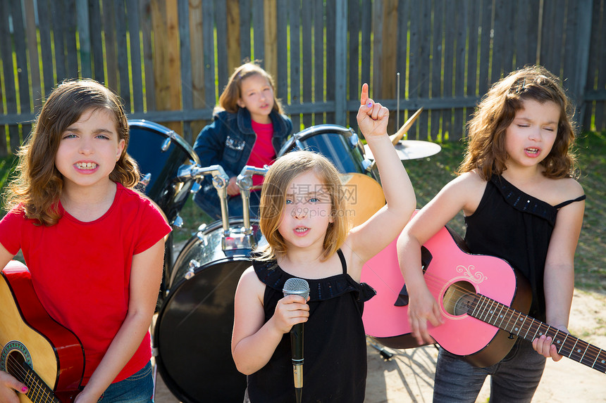 歌唱女歌手在后院现场演奏乐团歌手享受童年鼓手草地音乐家孩子眼睛闲暇仪器图片