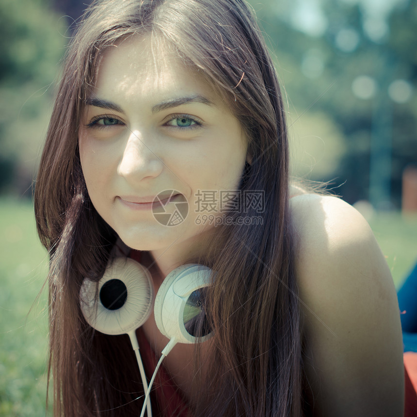 公园中美丽的女模美年轻女子耳机微笑长发潮人图片