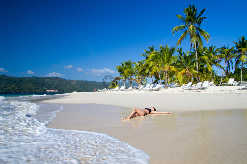女人在沙滩上放松热带旅行珊瑚天空海岸海浪女士棕榈成人闲暇图片
