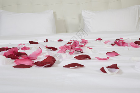 带有大床和红花的旅馆客房花瓣花朵家具白色房间卧室玫瑰房子奢华寝具背景图片
