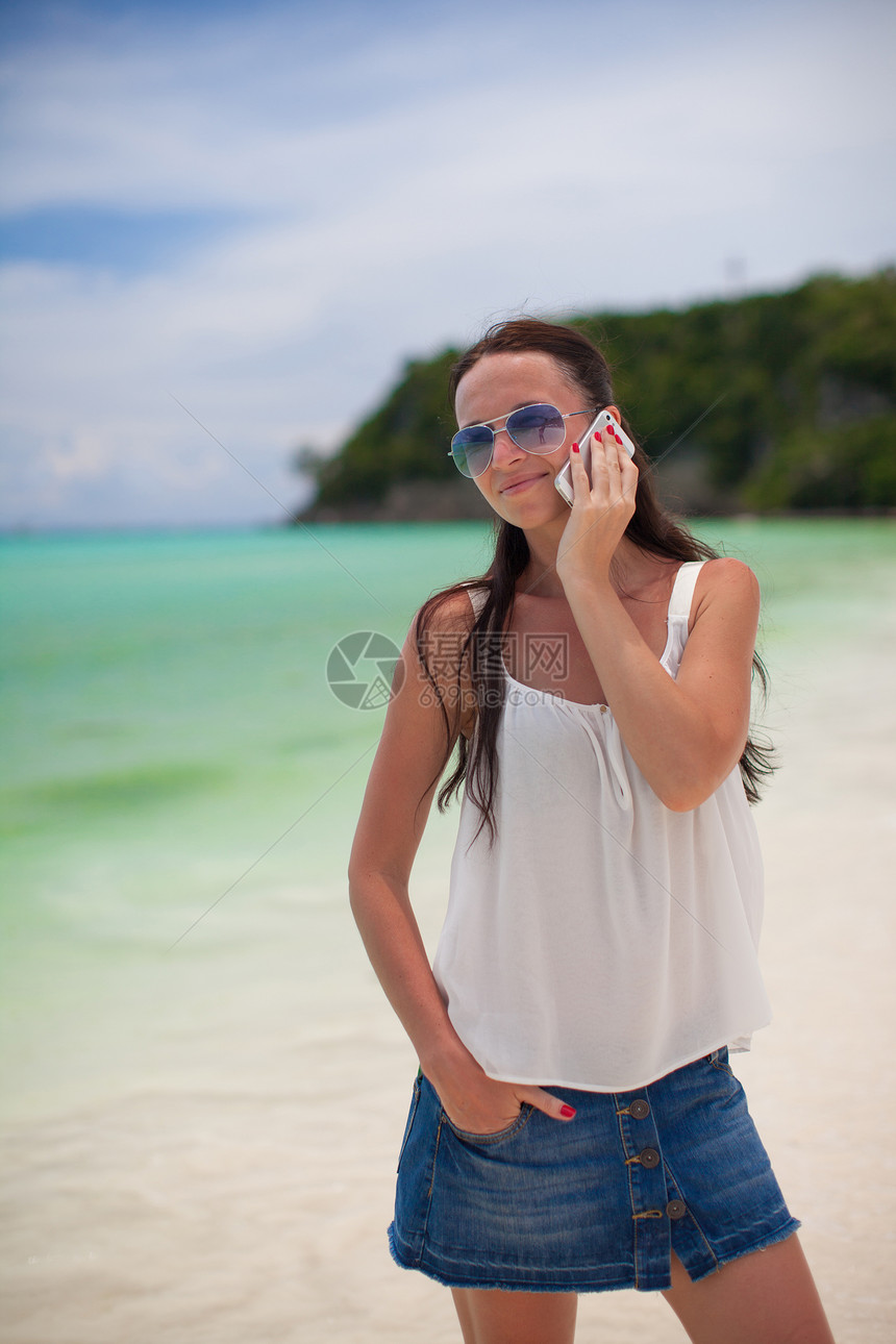 海滩上的年轻美女 在电话上聊天时说话图片