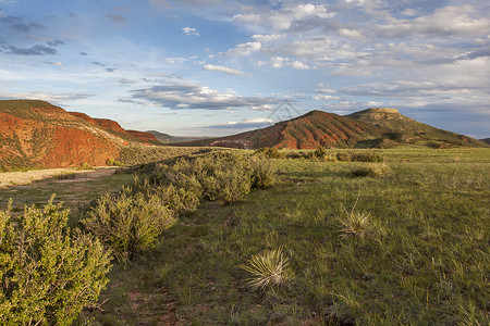 山山牧场前端草原崎岖石头草地红色悬崖绿色范围高清图片