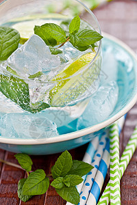 新鲜柠檬水玻璃冰块条纹吸管饮料稻草泉水柠檬照片蓝色背景图片