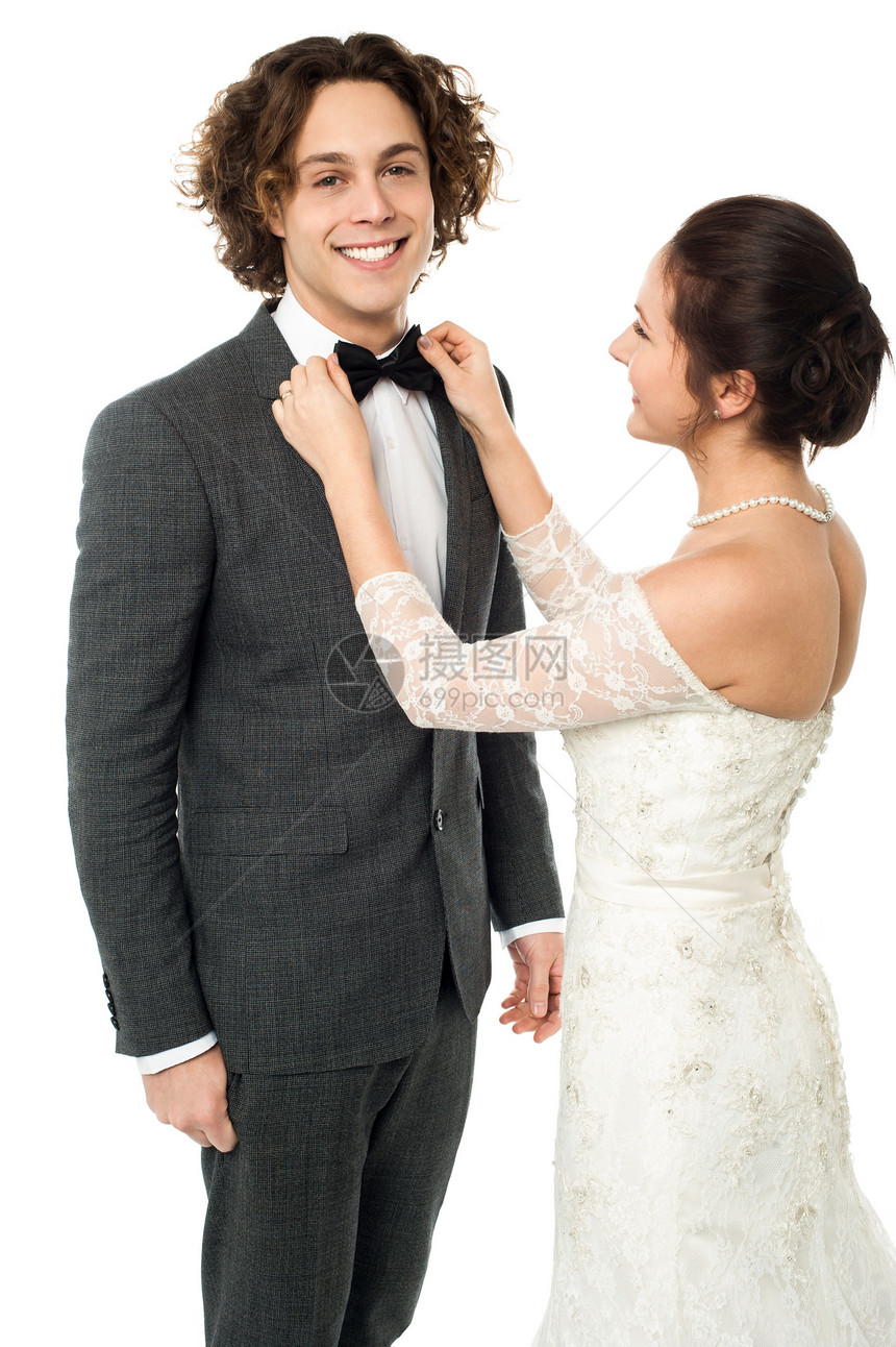 新娘调整她男人的领结冒充庆典魅力婚礼新郎仪式妻子夫妻套装女孩图片