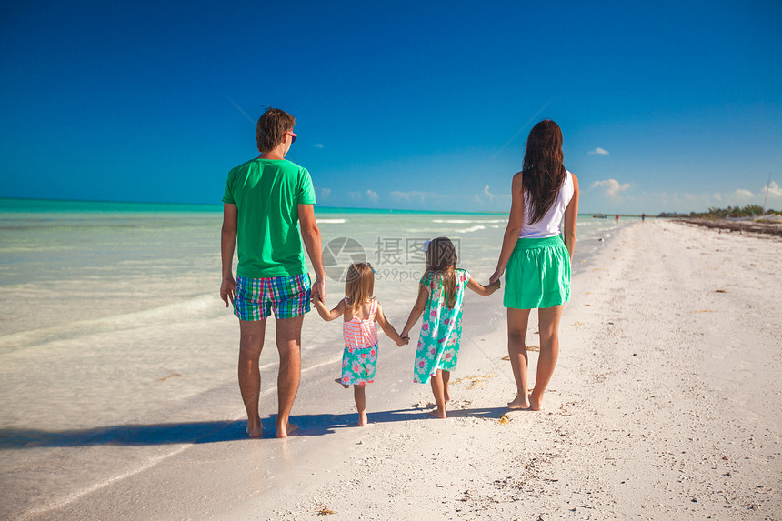 在海滩上行走的四人家庭背影图片