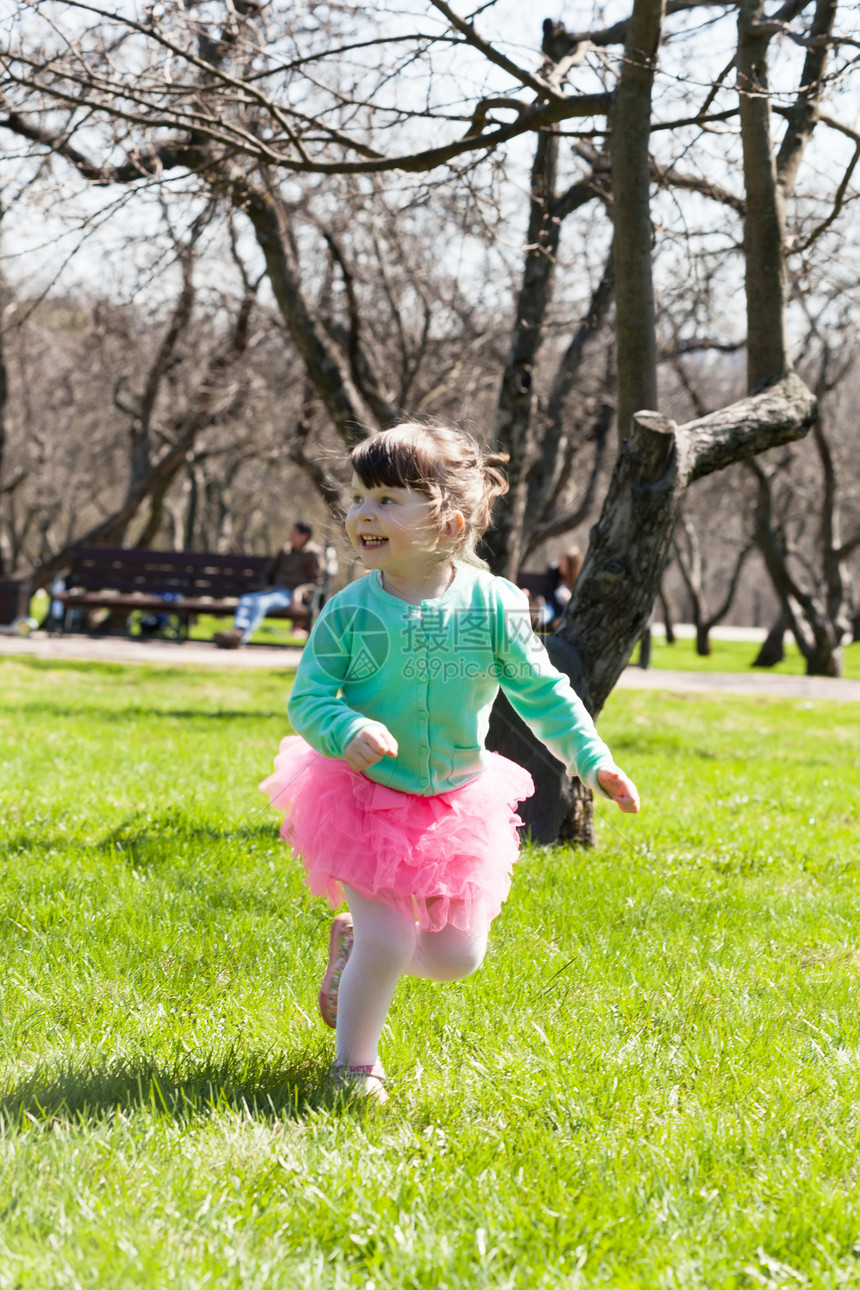 快乐的小女孩跑在春天公园图片