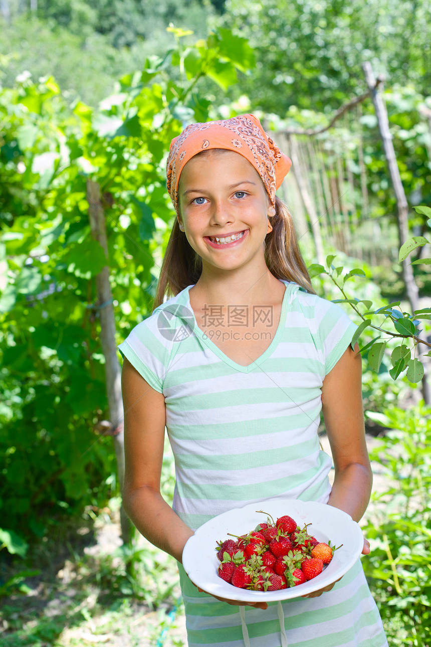 女孩拿着草莓享受花园孩子乐趣童年快乐马尾辫微笑诱惑小吃图片