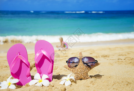 沙滩拖鞋沙沙滩上有太阳眼镜的浮流和海星太阳镜阳光假期海浪花朵凉鞋季节气候旅行热带背景