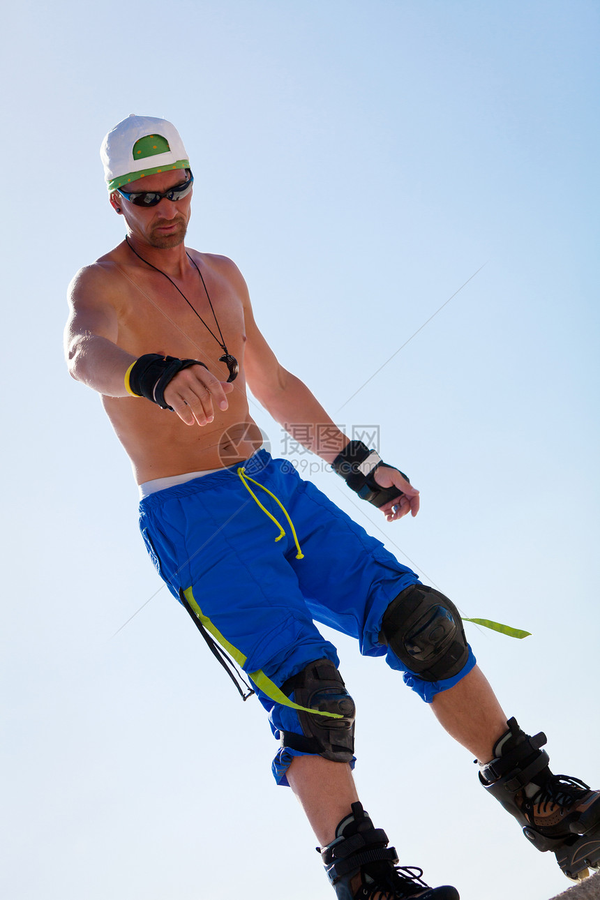 夏季户外穿着内滑鞋的青年男子沥青轮滑微笑成人海滩天空蓝色溜冰者诡计乐趣图片