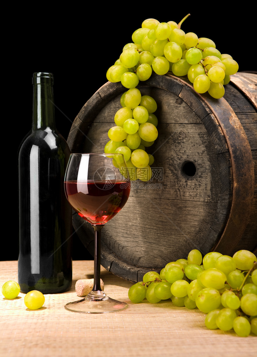 红酒和绿葡萄 以古老的葡萄桶为背景图片