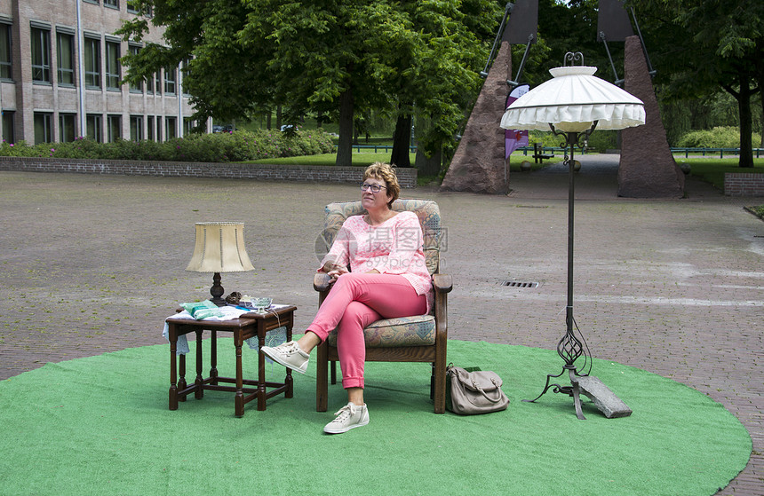 坐在有桌和灯的椅子上的公园里的妇女图片
