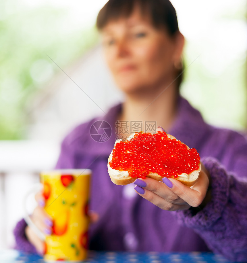 配有红鱼子酱三明治的妇女图片