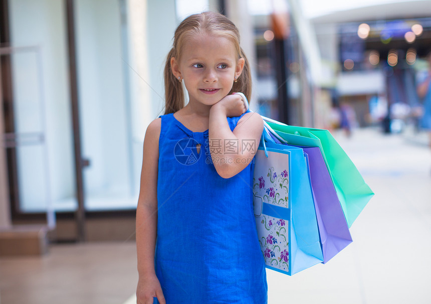在商场上拿着购物袋的小可爱女孩的肖像女性青年孩子购买者礼物闲暇市场店铺购物者幸福图片