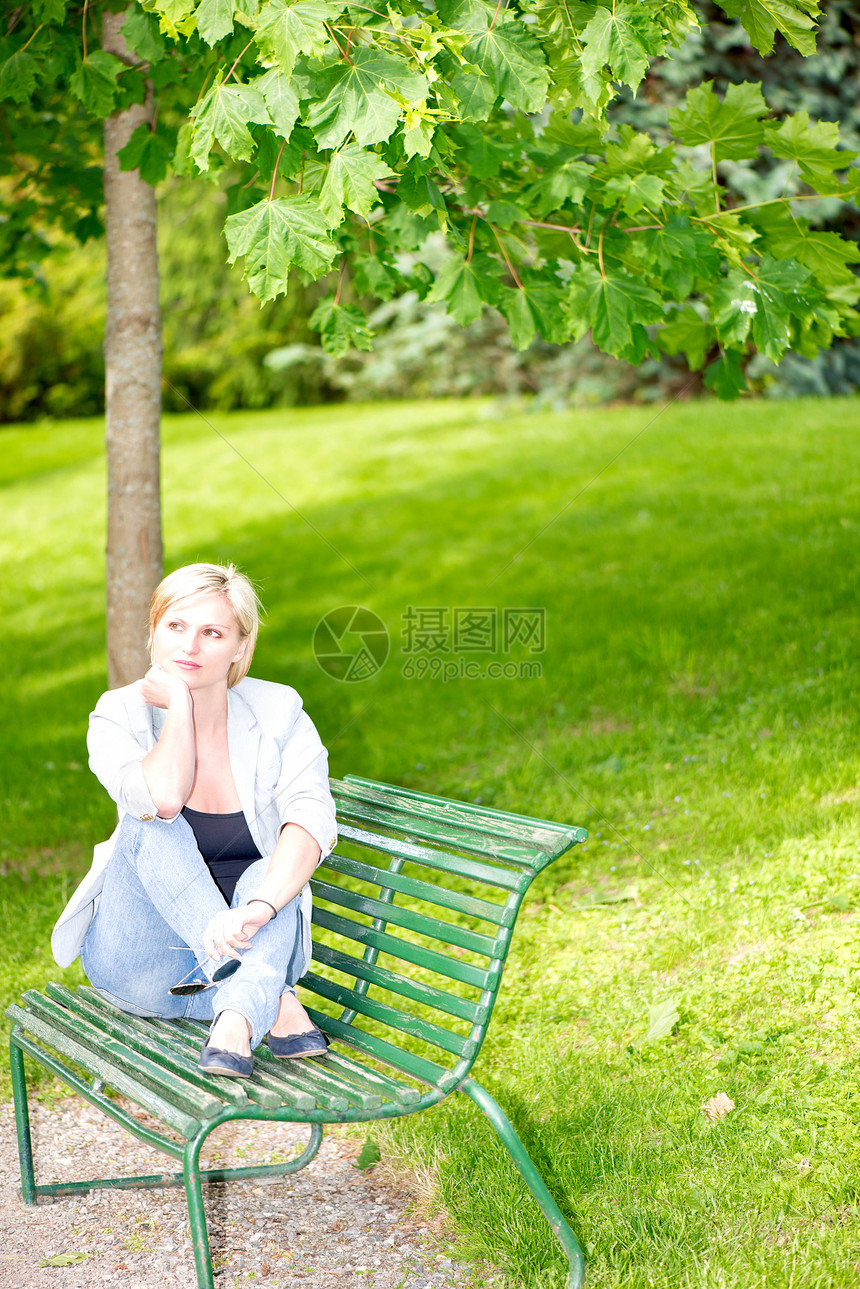 坐在公园长椅上的年轻妇女女士金发女郎女性女孩青年白色绿色图片