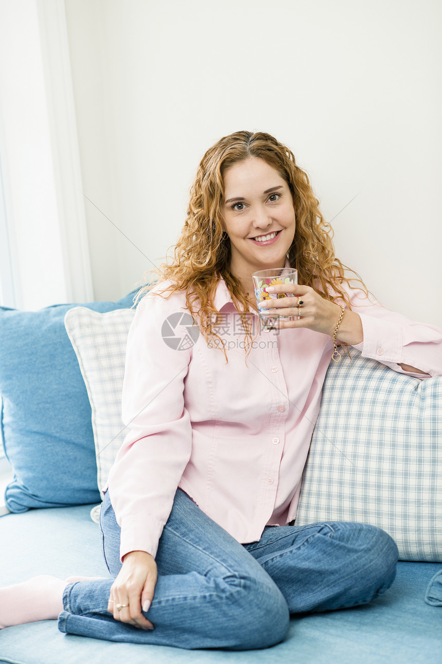妇女在家里放松枕头饮料房子住宅成人沙发白色女性粉色微笑图片