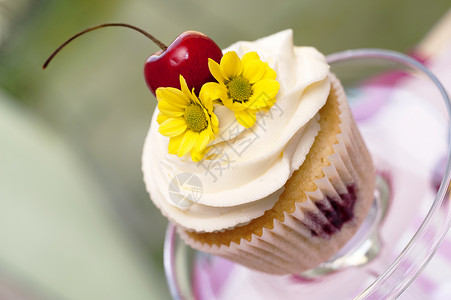樱桃松饼与樱桃花和鲜花的杯饼奶油桌子杯子小雨香草鞭打蛋糕玻璃甜点烘焙背景