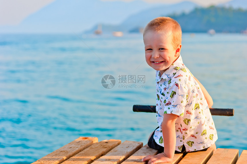 快乐的小男孩坐在码头上图片