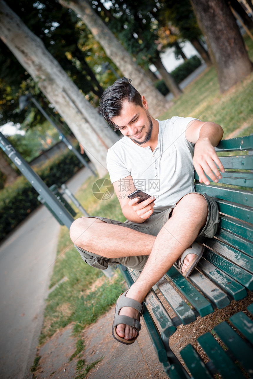 时尚男子在电话上沟通呼唤长椅日常生活手机年轻人潮人短信公园图片