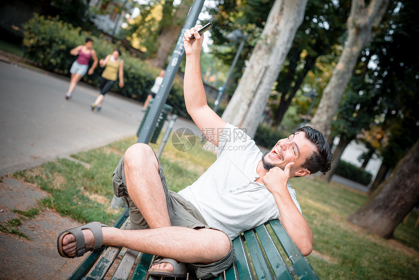 时尚男子在电话上日常生活年轻人呼唤长椅微笑潮人公园沟通手机图片