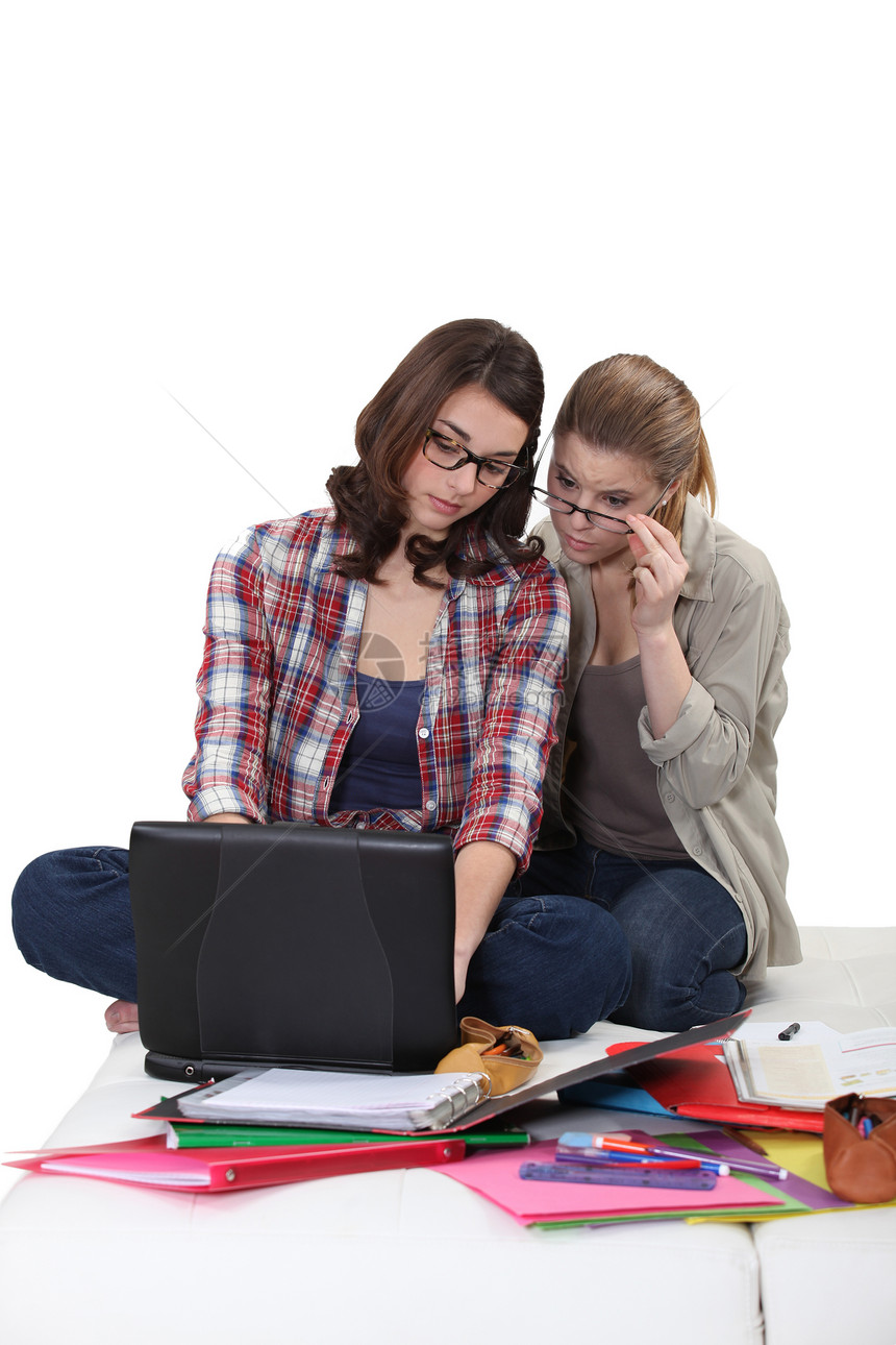 在笔记本电脑上工作的女学生白色团队眼镜女孩们地面微笑膝盖朋友们教科书学生图片